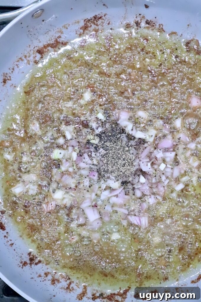 shallots and black pepper in liquid in a skillet