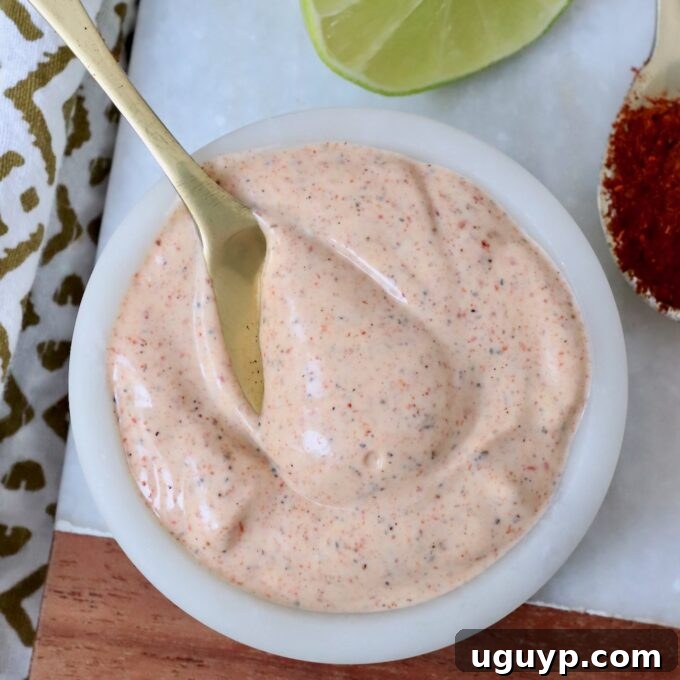 chili lime dressing in a white bowl with a gold spoon