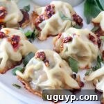 Thai basil chicken dumplings on a plate topped with chili crisp and thai basil leaves