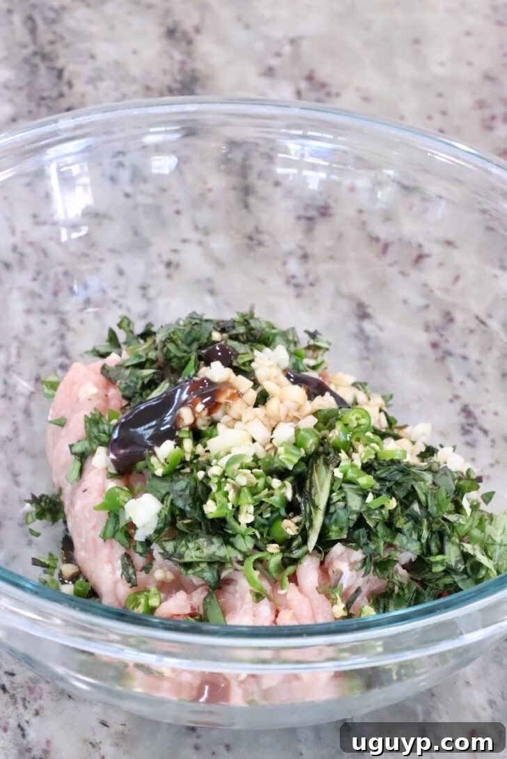 ground chicken with fresh herbs and garlic in a glass bowl