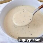 miso caesar dressing in a bowl with a spoon dipping the dressing out of the bowl