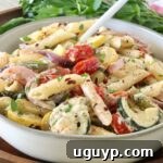 creamy pasta primavera in a bowl with a fork, with fresh parsley in the background