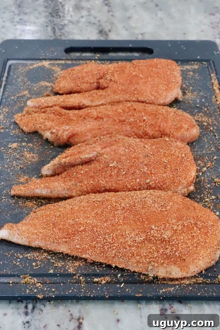 seasoned raw chicken breasts on a cutting board