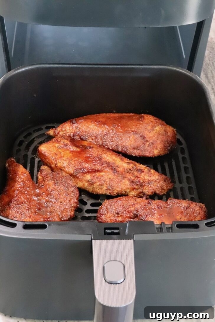 cooked chipotle honey chicken breasts in a an air fryer basket