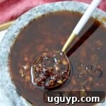 Calabrian chili crisp in a gray bowl with a white and gold spoon dipped in the sauce
