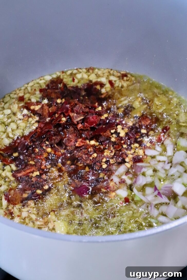 pot filled with oil, garlic, shallots, and chopped dried chilies on the stove