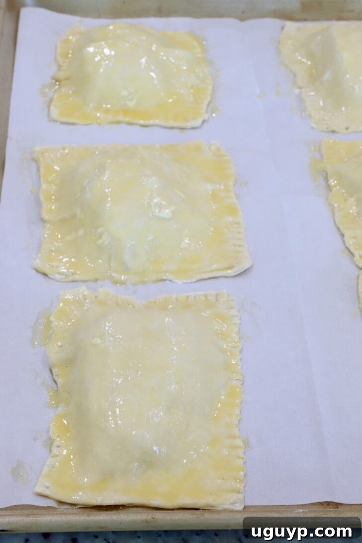 unbaked tarts on a parchment-lined baking sheet brushed with egg wash