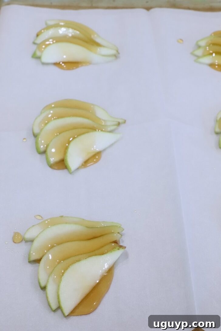 sliced pears topped with honey on a sheet of parchment paper on a baking sheet
