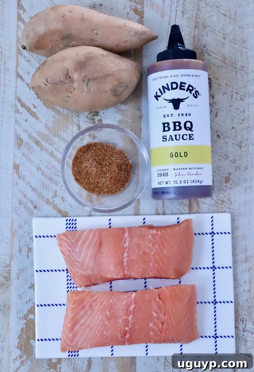 Raw salmon fillets on a checkered plate, accompanied by sweet potatoes, BBQ sauce, and a bowl of spices on a rustic wooden surface.