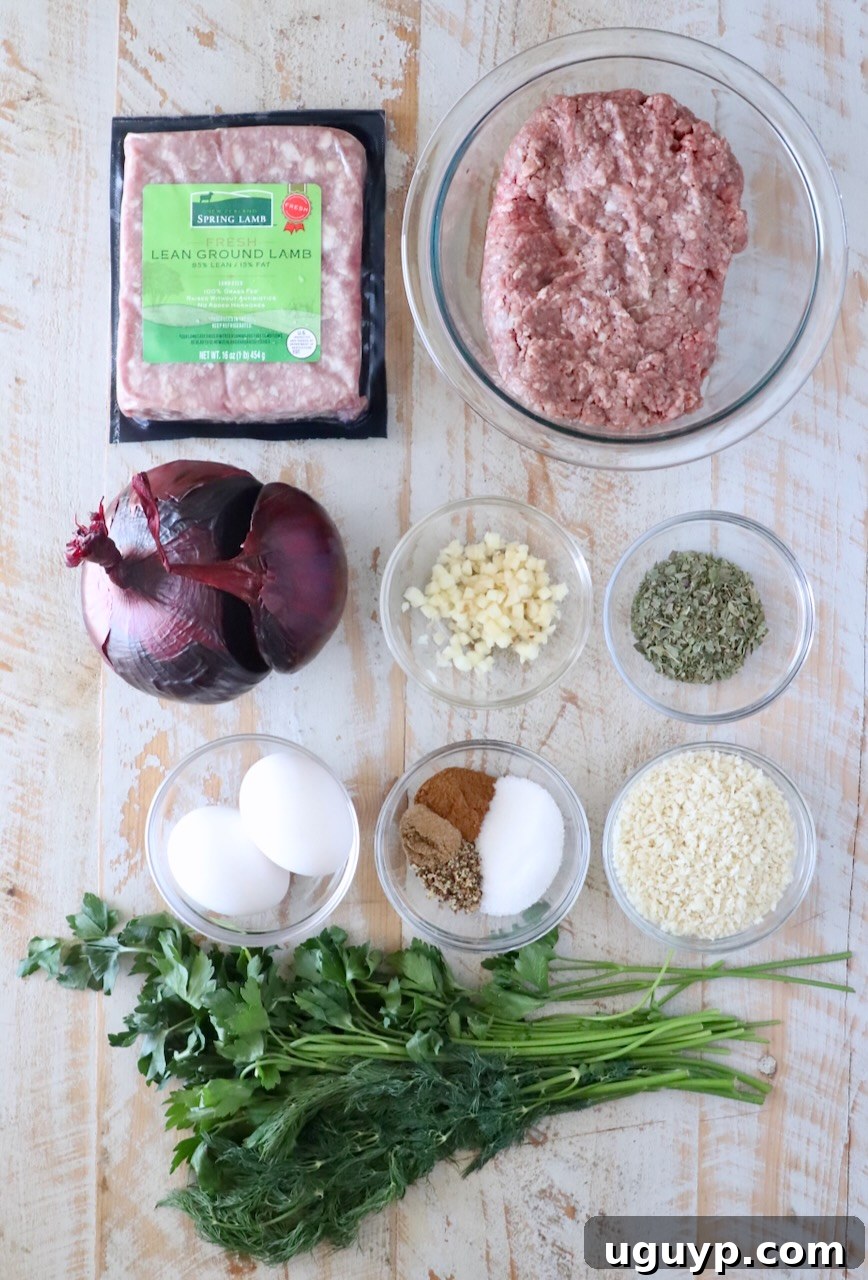 Ingredients for gyro meatballs on wooden surface: packaged lean ground lamb, ground beef in a glass bowl, chopped garlic, dry herbs, eggs, spices, panko breadcrumbs, red onion, fresh parsley, and dill.