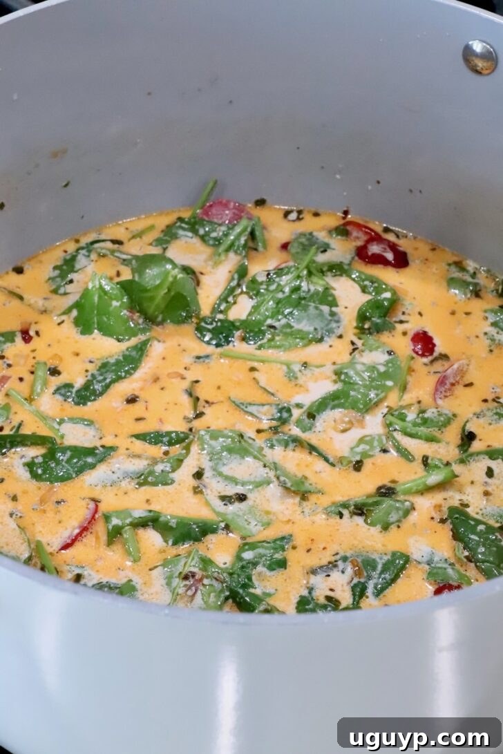 creamy tuscan sauce with spinach leaves and sun dried tomatoes in a sauce pan