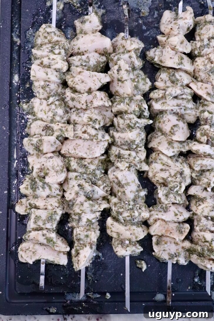 skewered cubes of marinated chicken on a black cutting board