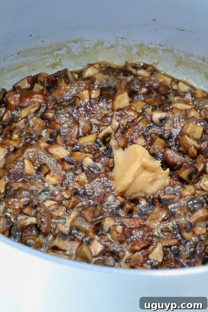 mushroom jam in a pot on the stove with a scoop of white miso paste
