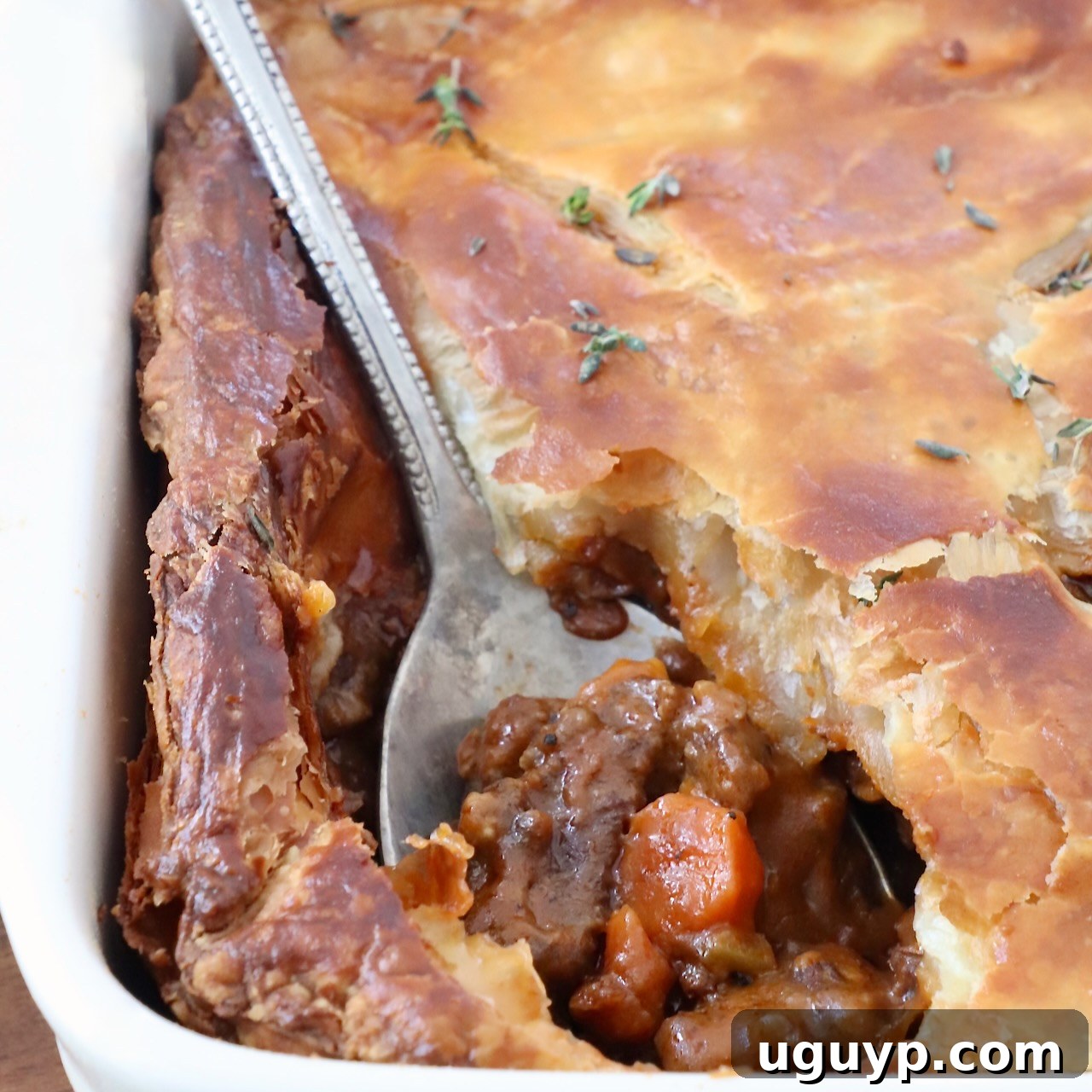 serving spoon in a beef pot pie in a baking dish