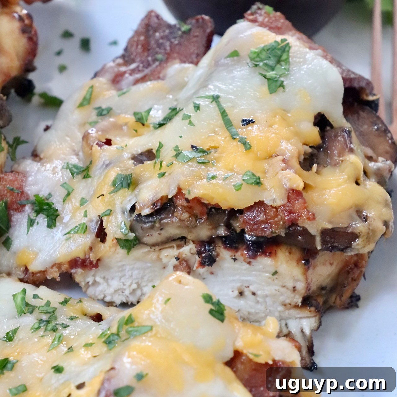 grilled chicken topped with bacon and cheese sliced in half on plate