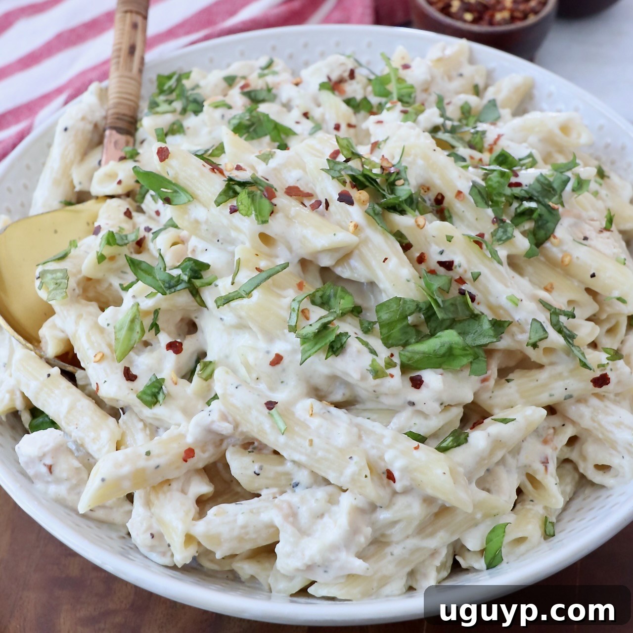 garlic parmesan chicken pasta in bowl with serving spoon