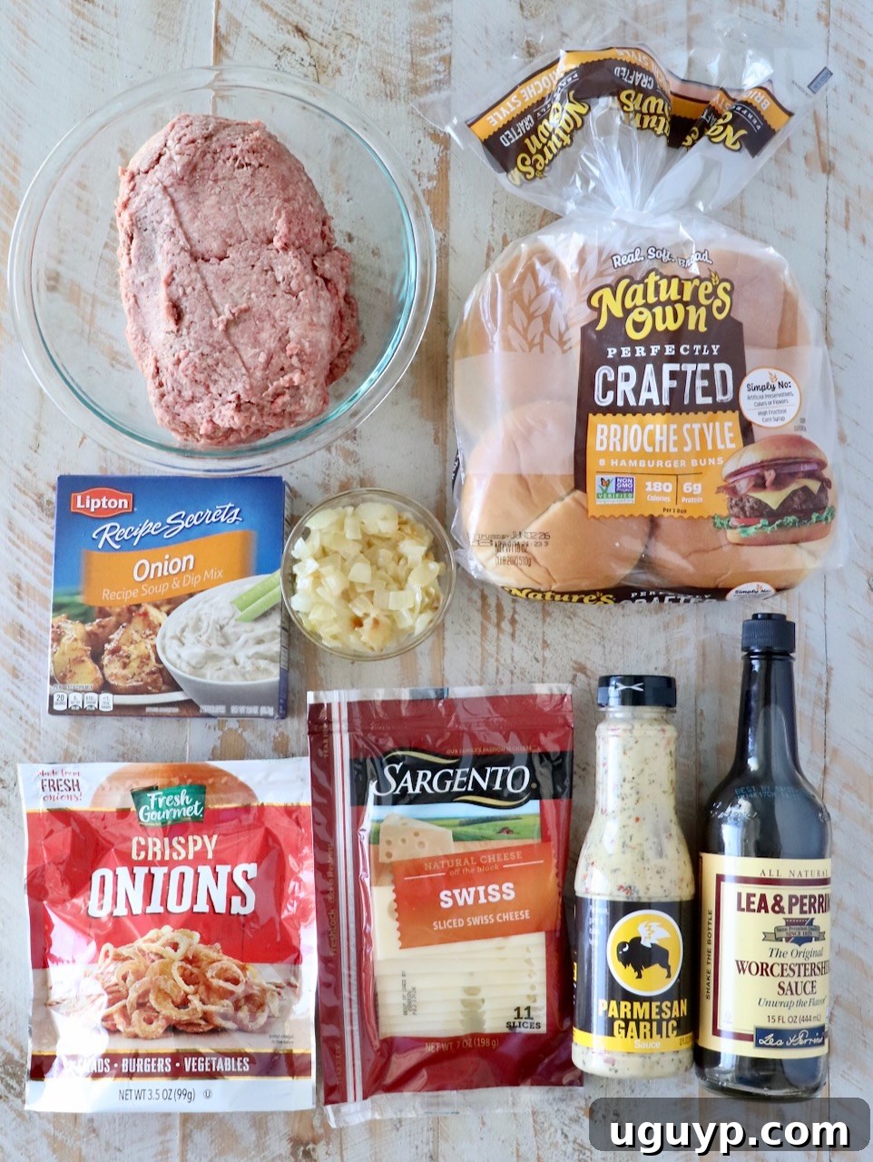 ingredients for french onion burgers on a white wood board