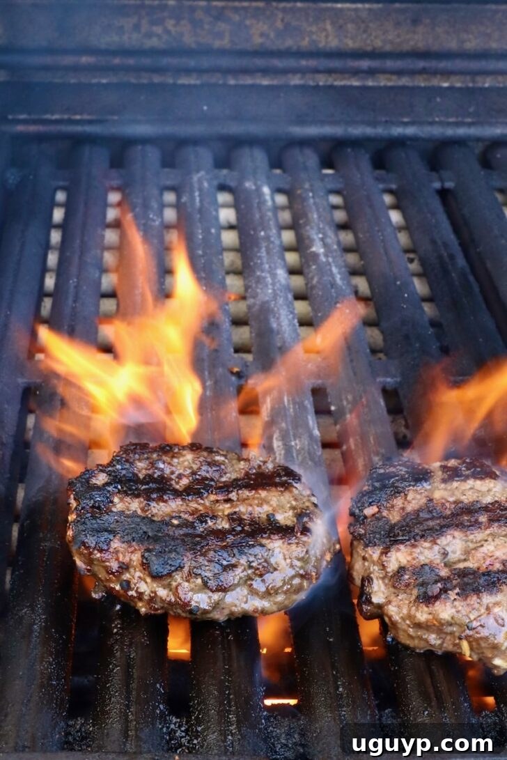 grilled burger patties on a grill with flames