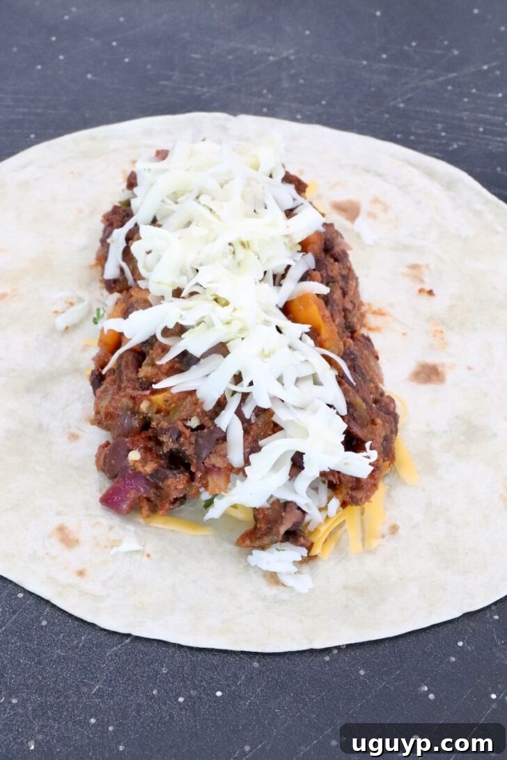 Cheesy Bean & Rice Burrito Recipe – Quick Weeknight Meal 11 bean filling in the middle of a tortilla topped with shredded pepper jack cheese