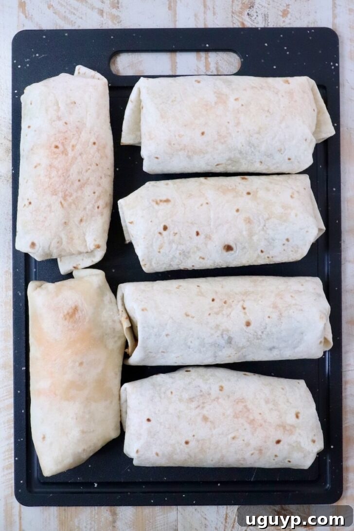 Cheesy Bean & Rice Burrito Recipe – Quick Weeknight Meal 13 six prepared burritos on a cutting board