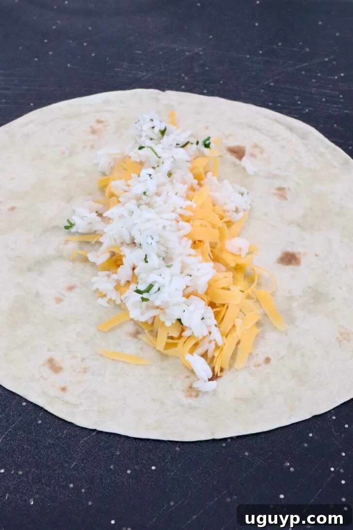 Cheesy Bean & Rice Burrito Recipe – Quick Weeknight Meal 9 shredded cheddar cheese and cilantro lime rice in the middle of a tortilla