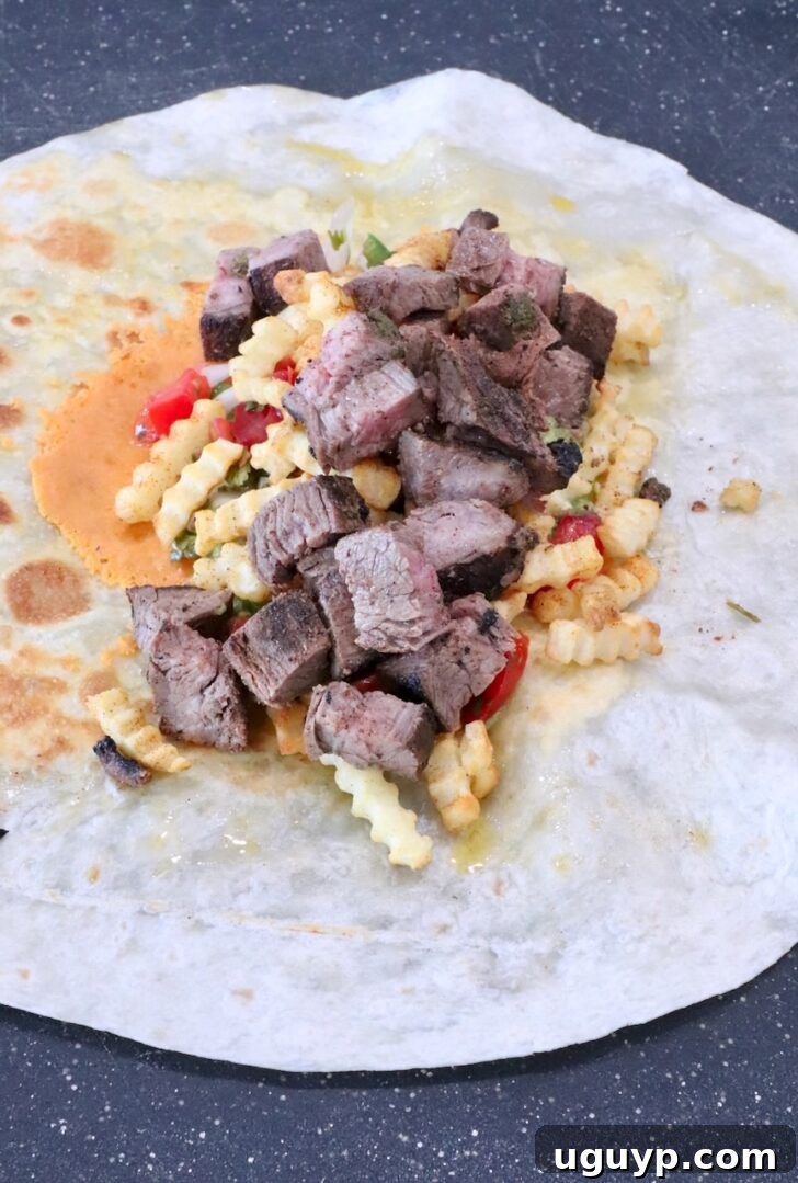 Classic California Burrito Recipe with Carne Asada & Fries 8 carne asada and french fries on top of pico de gallo in the middle of a tortilla