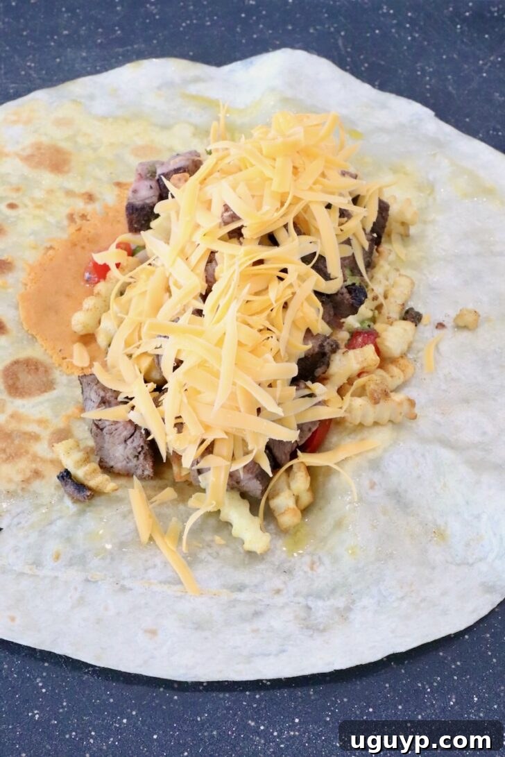 Classic California Burrito Recipe with Carne Asada & Fries 9 shredded cheese on top of carne asada in the middle of a tortilla