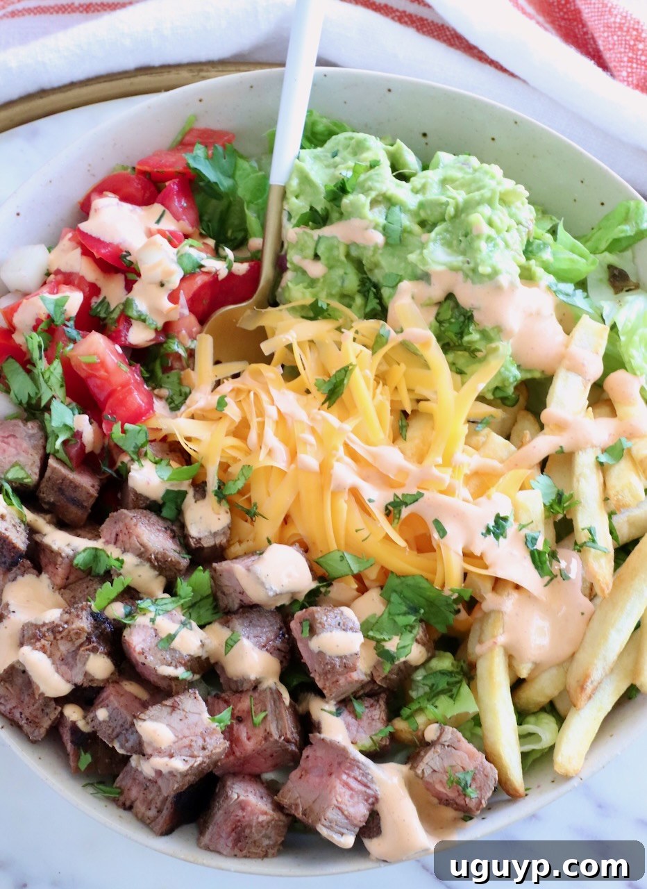 California Burrito Bowl Recipe: Chipotle-Style Carne Asada Bowl 2 bowl filled with diced carne asada, shredded cheese, guacamole, and pico de gallo with a fork in the middle