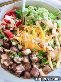 California Burrito Bowl Recipe: Chipotle-Style Carne Asada Bowl 10 bowl filled with diced carne asada, french fries, cheese, pico de gallo and guacamole, with a fork in the middle