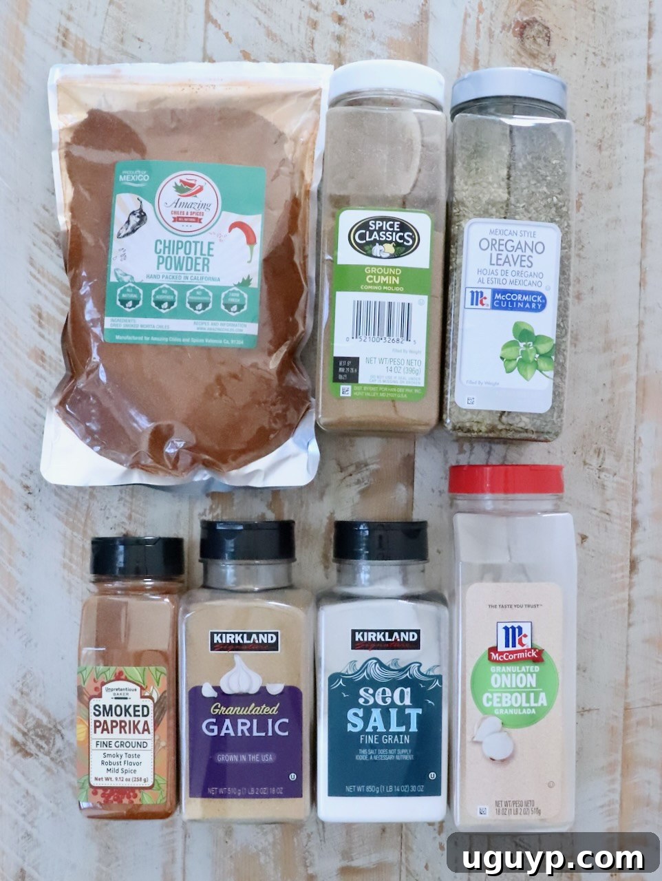 spices in plastic containers for chicken tacos seasoning lined up on a white wood table