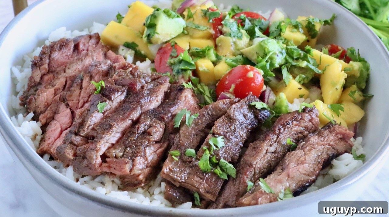 sliced steak in a bowl on top of rice with mango avocado salsa