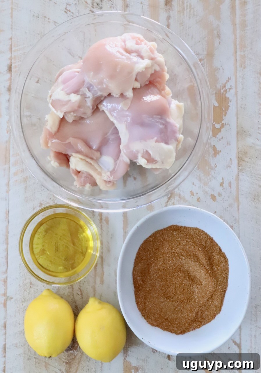 Homemade Chicken Shawarma Tacos Recipe 5 raw chicken thighs in a glass bowl, next to a small bowl of oil and seasoning mix, and two lemons