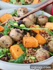 salad in a bowl topped with cranberry meatballs, butternut squash and edamame