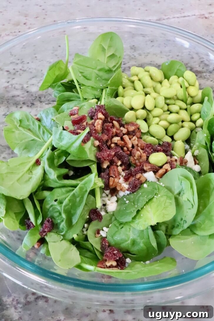 spinach in a large bowl with chopped nuts and edamame